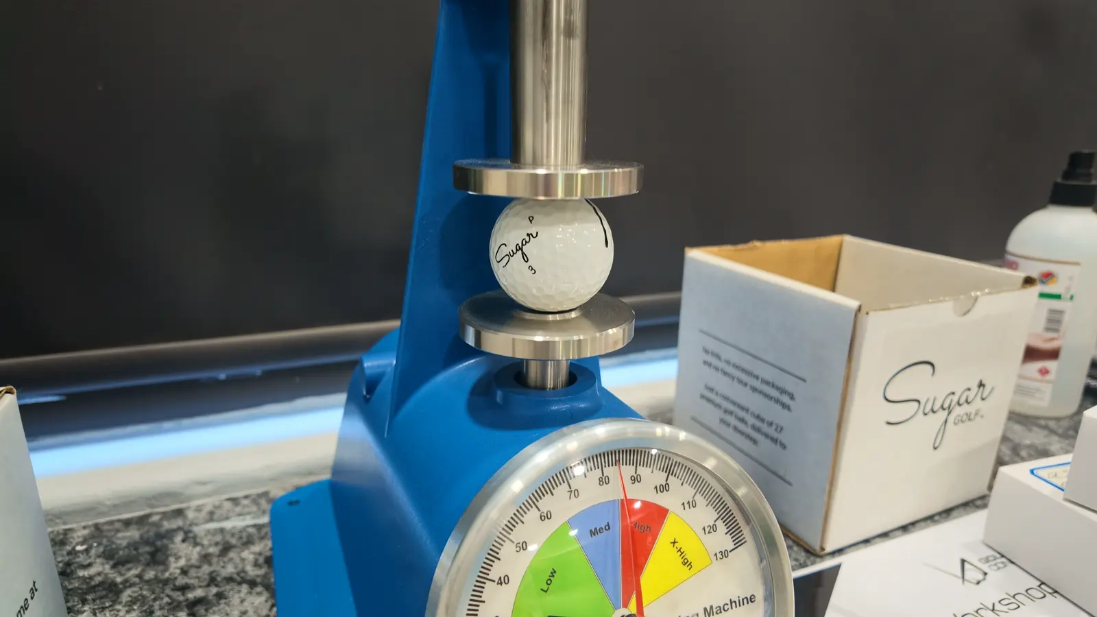A golf ball under the compression tester on the counter at Golf Concepts