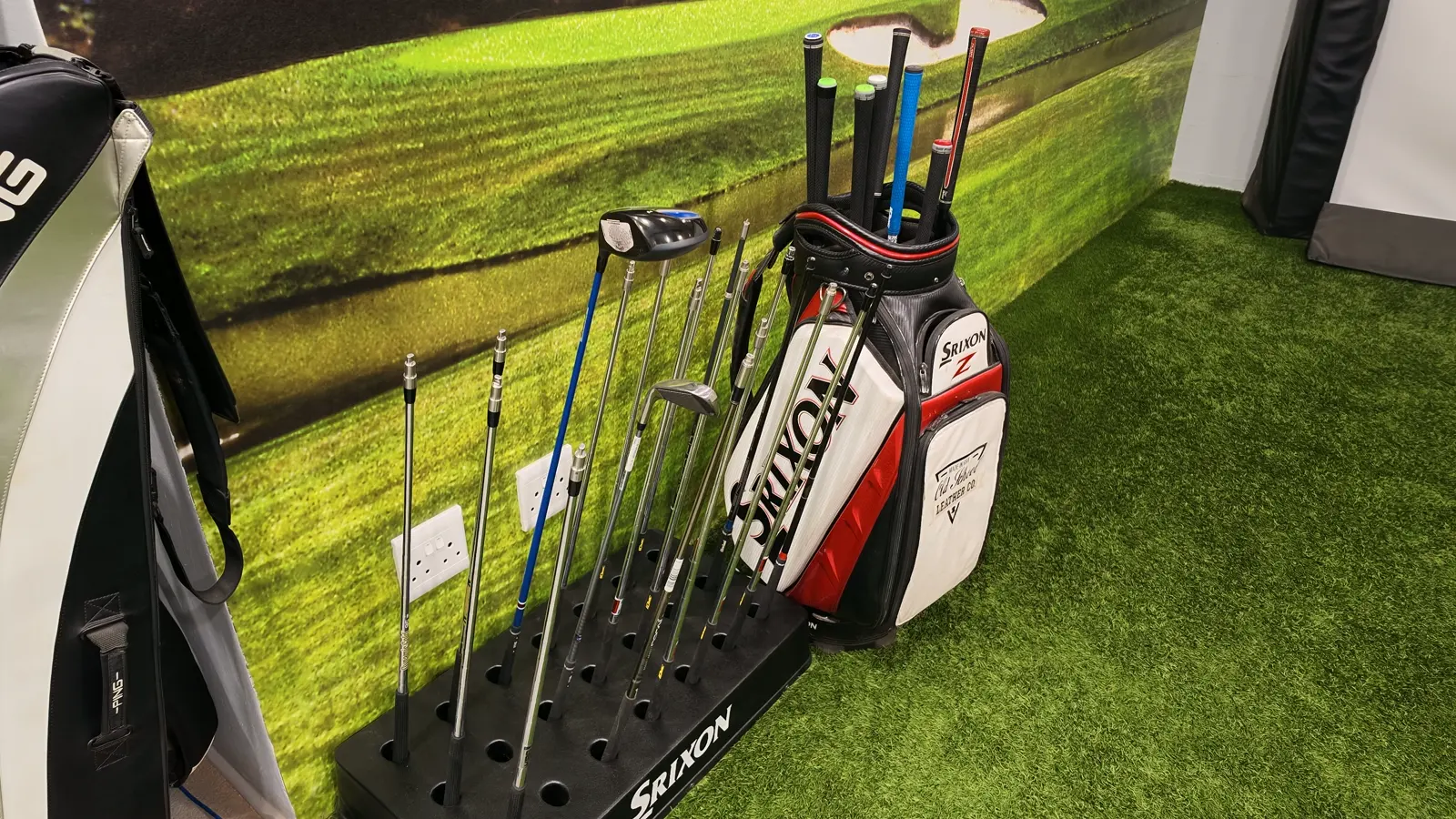 A shaft rack and a Srixon tour bag against the turf wall at Golf Concepts