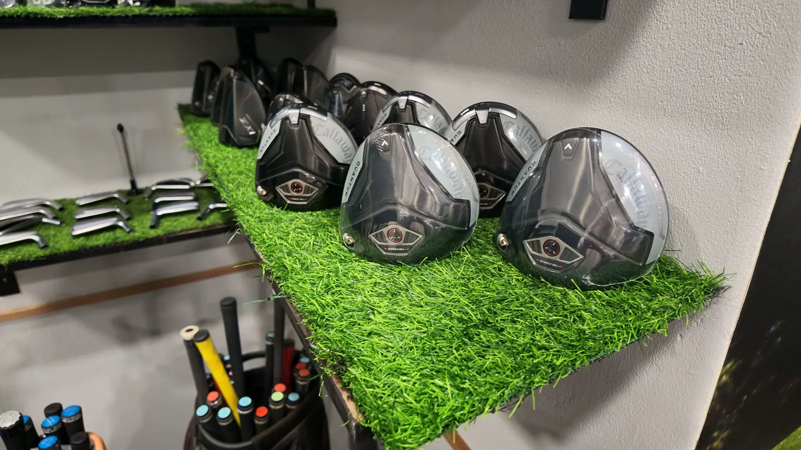 The demo wall at Golf Concepts — a row of Callaway driver heads on the turf shelves