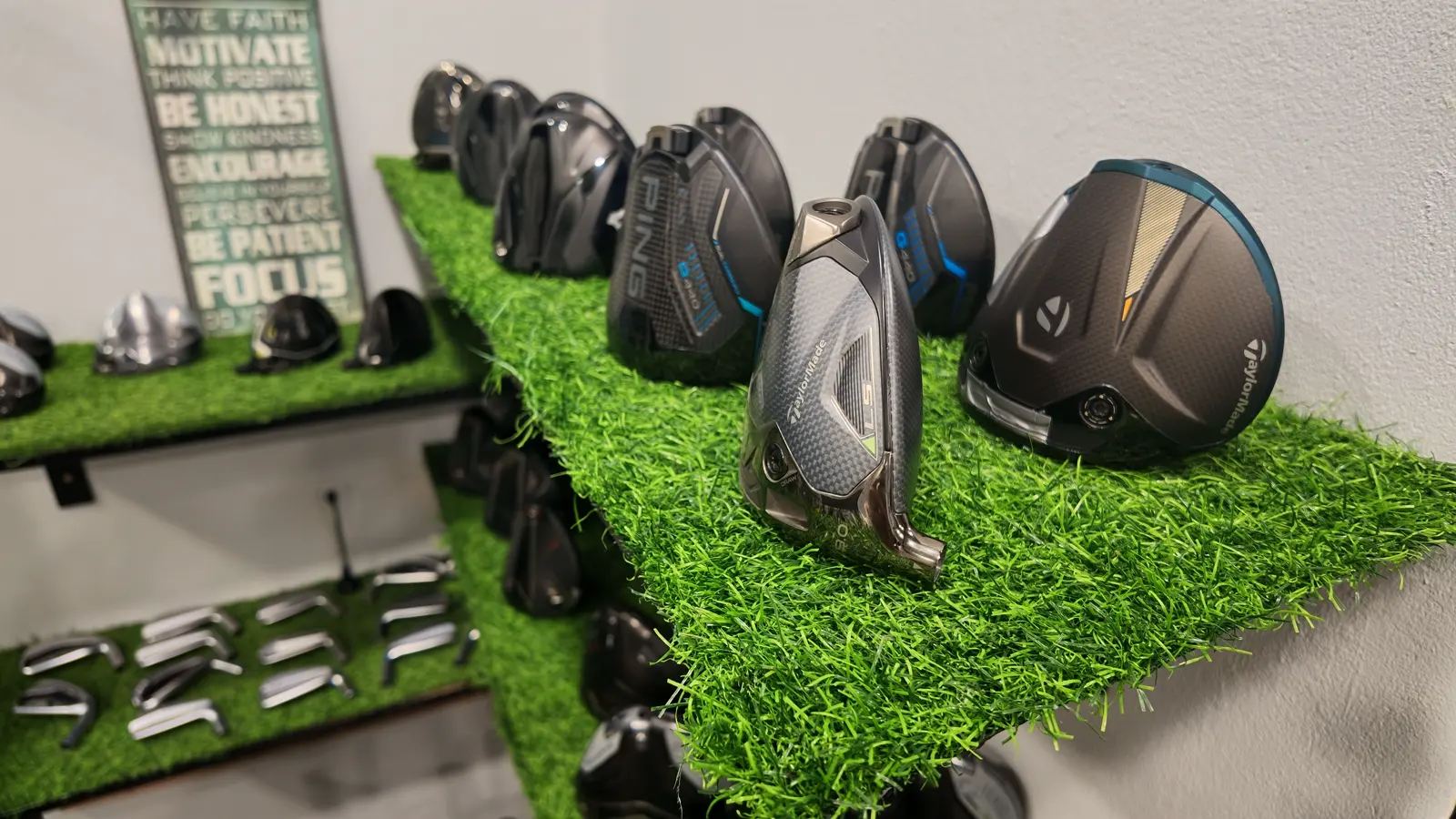 Driver and fairway wood heads on the turf shelves at Golf Concepts