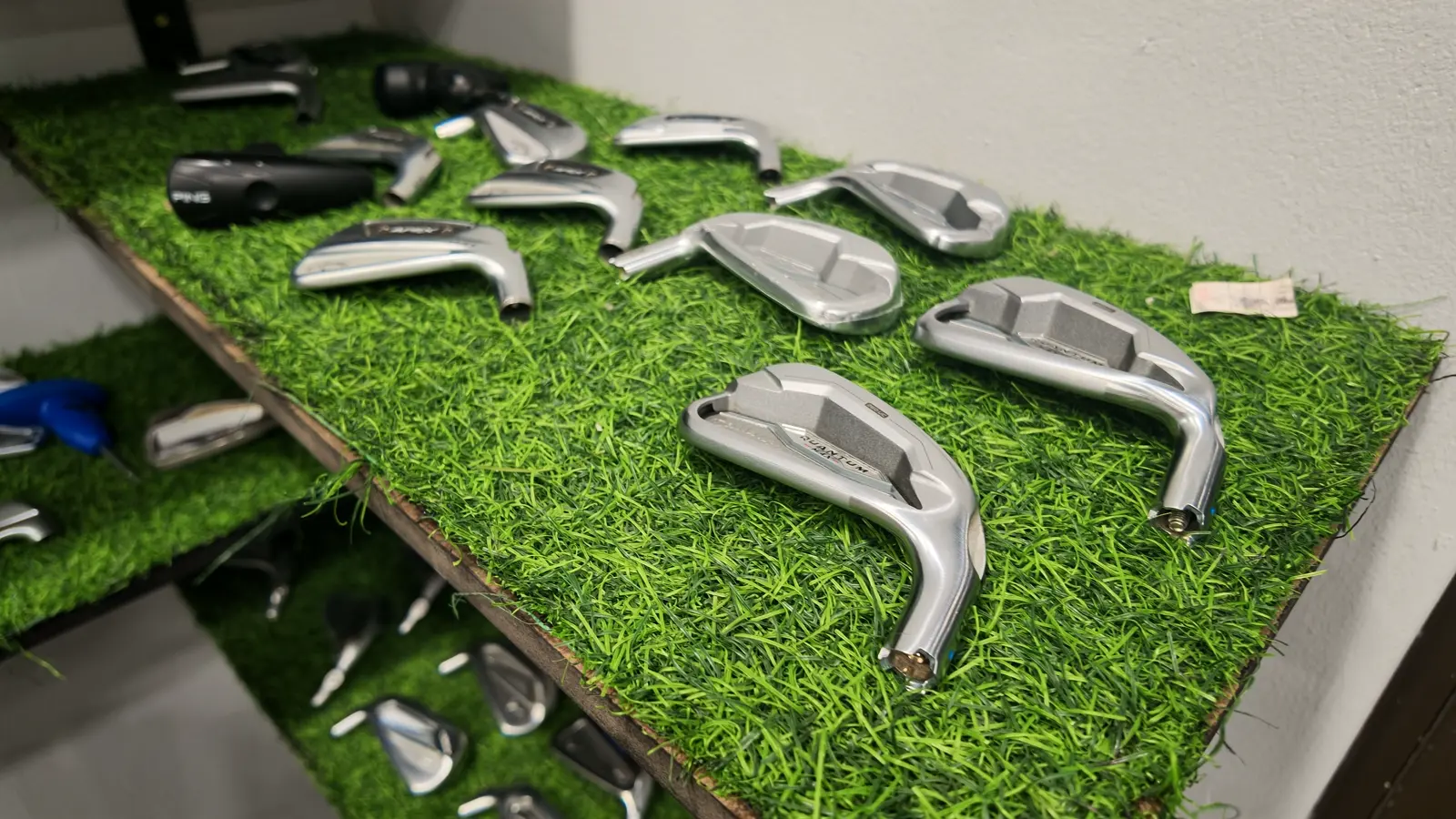 Iron heads laid out on a turf shelf at Golf Concepts