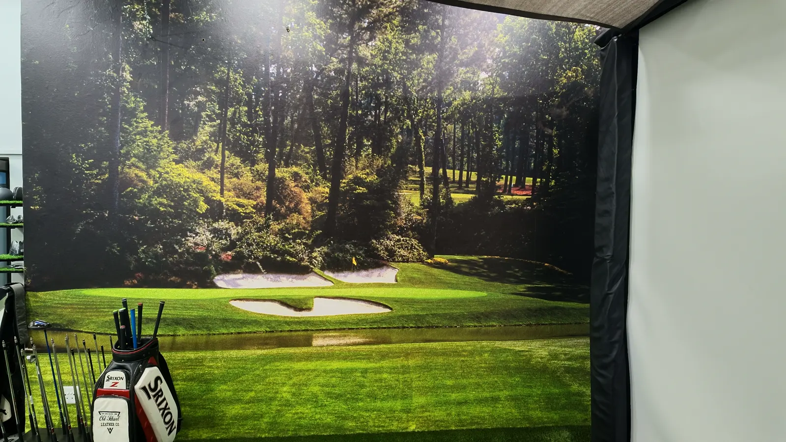 The fitting bay at Golf Concepts, with a tour bag in front of the simulator screen