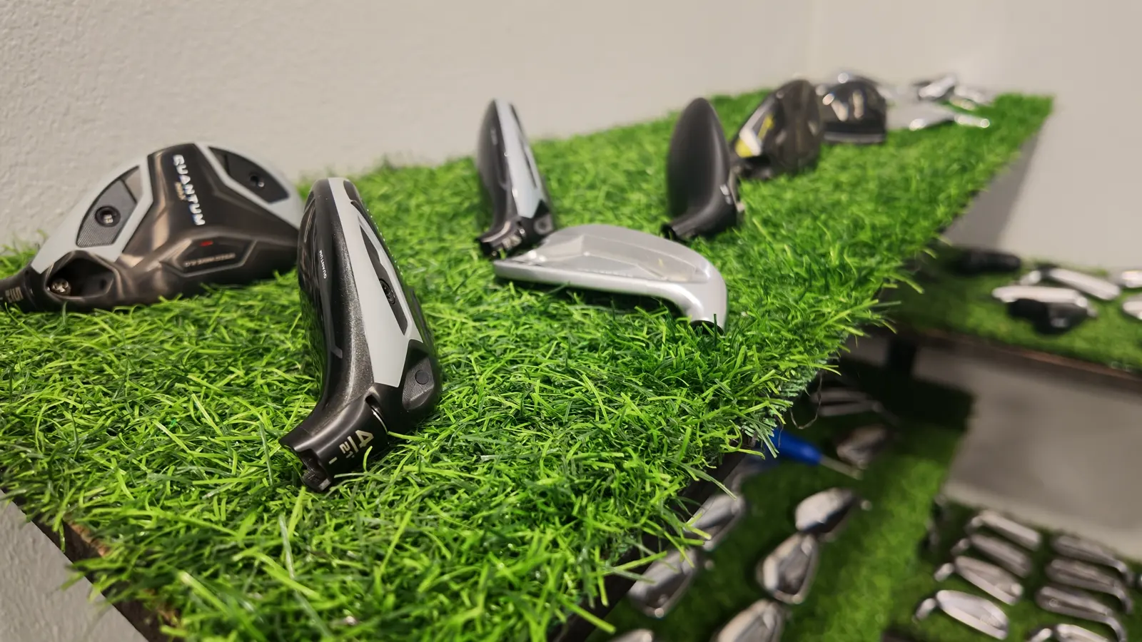 Fairway wood and hybrid heads on the turf shelves inside the Golf Concepts store
