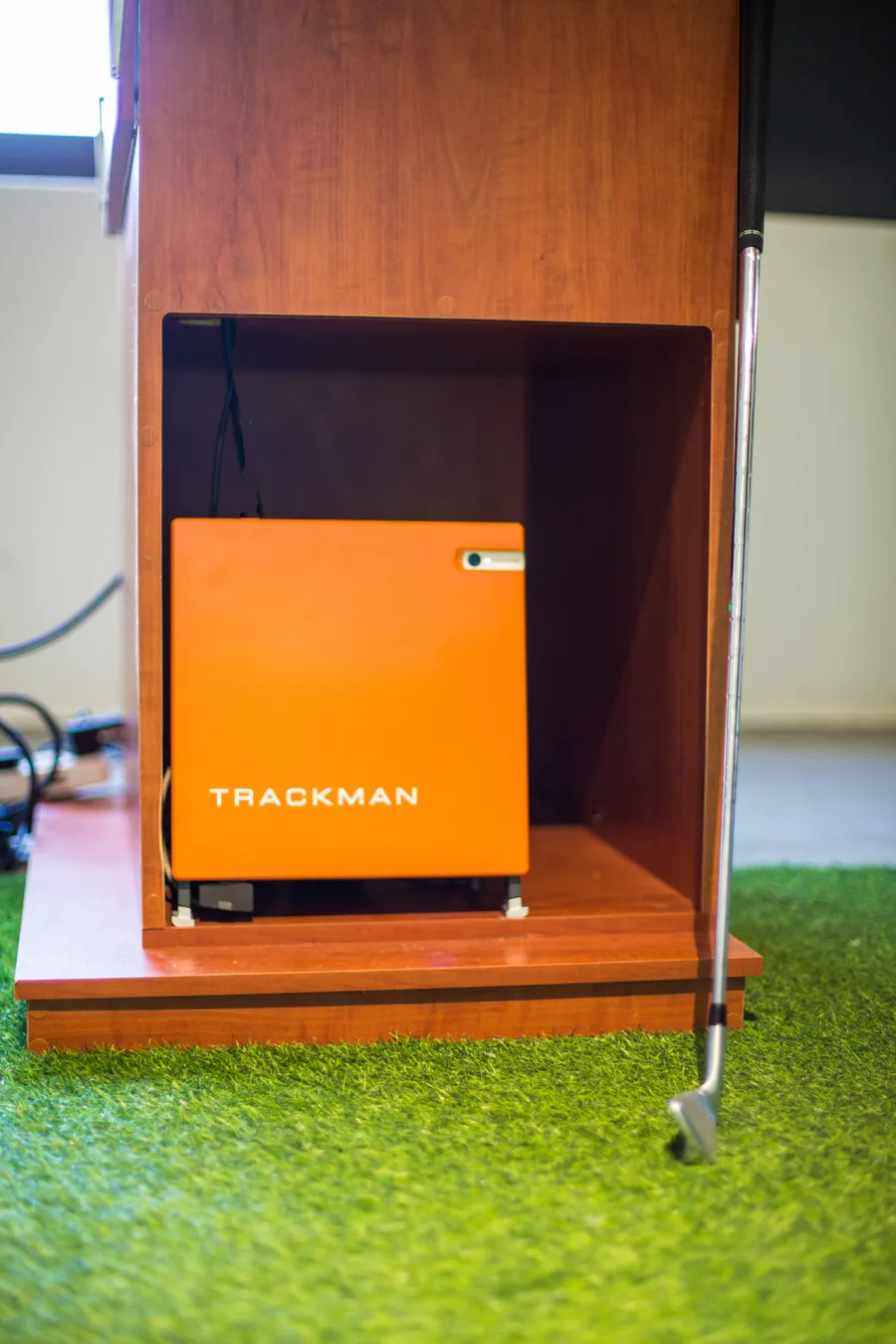 The orange TrackMan launch monitor unit installed in its cabinet in the Golf Concepts studio